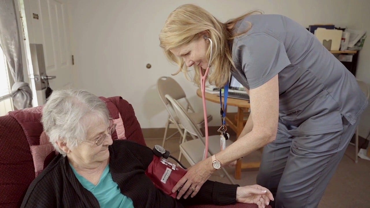 Nurse taking blood pressure of older adult woman