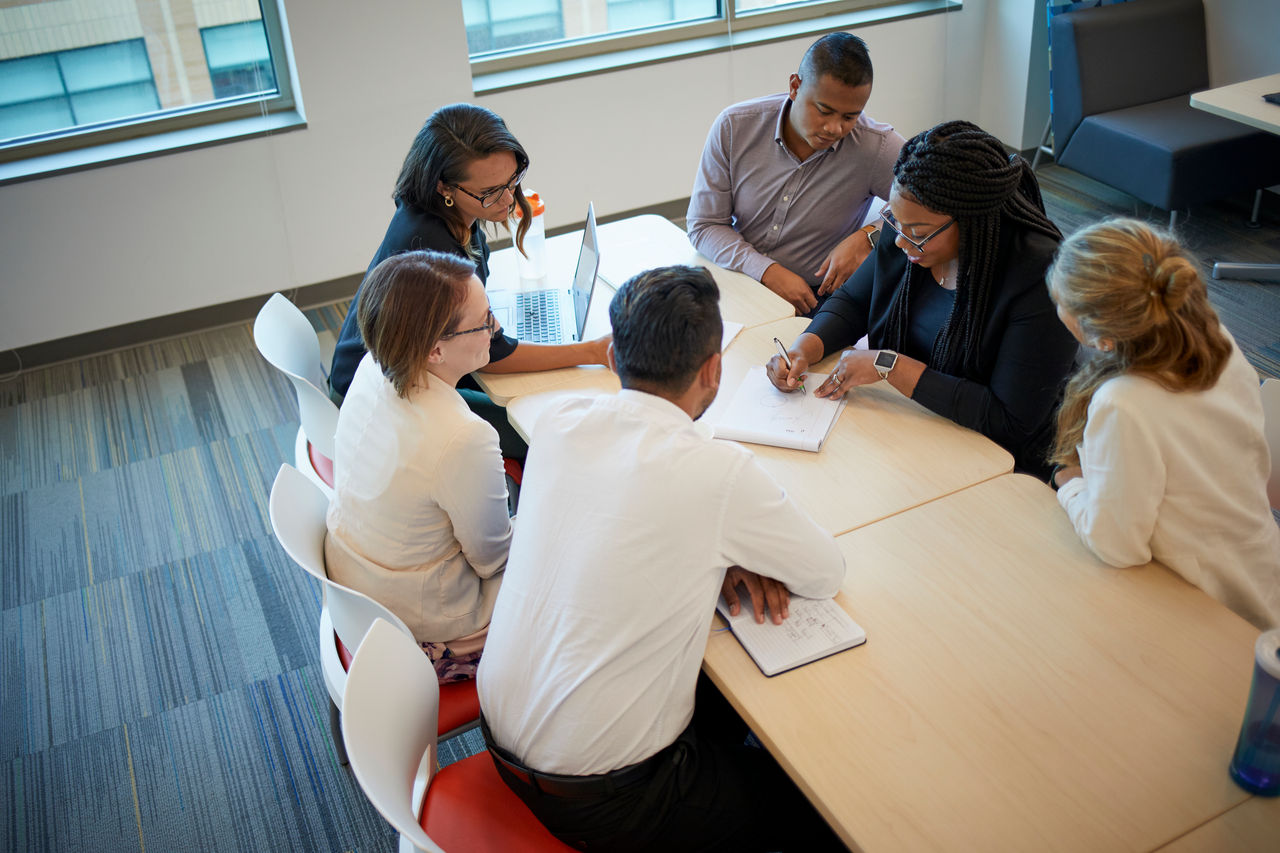 Group of men and women huddled around desk