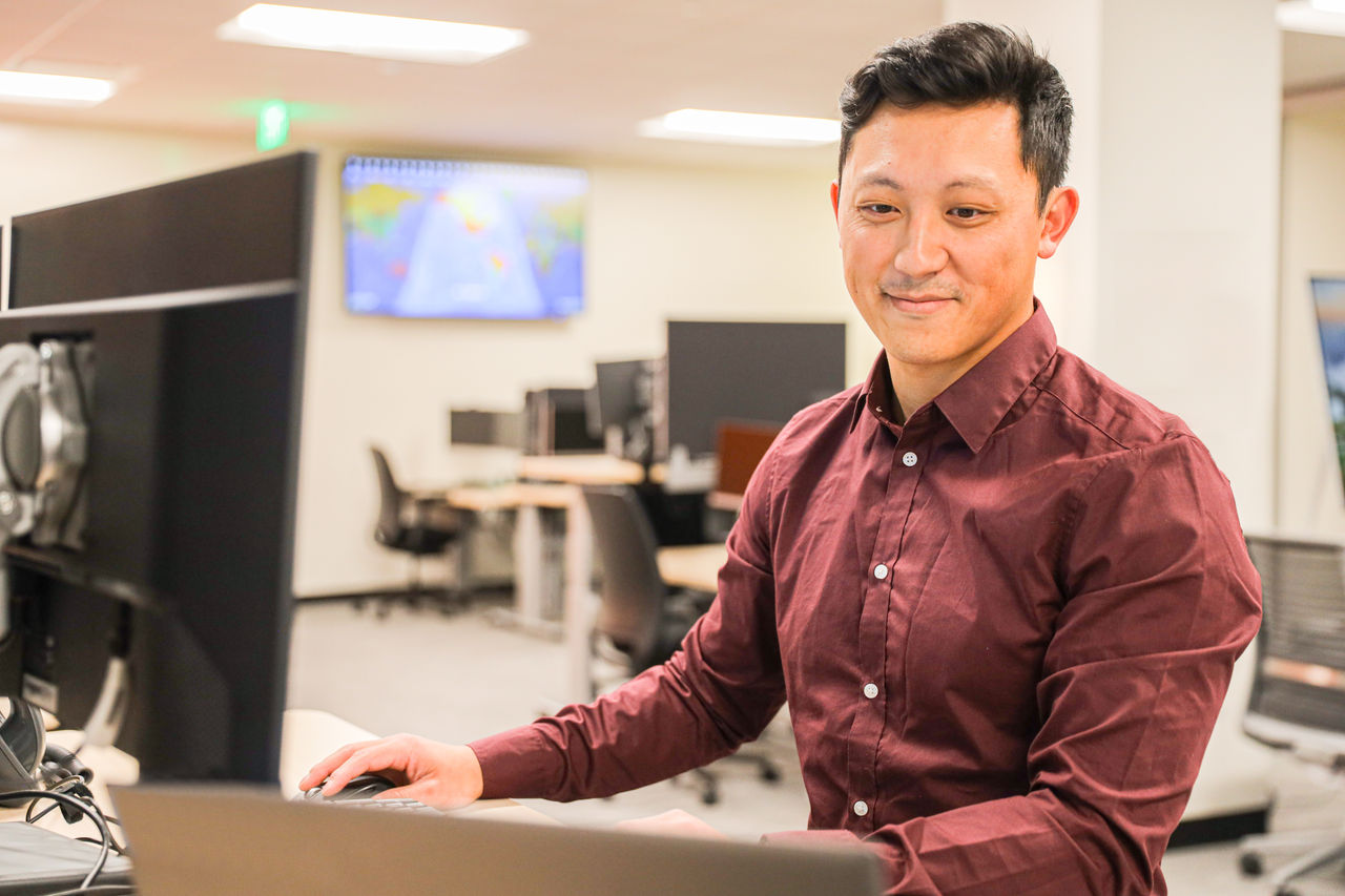 Andrew L., Associate Tech Support Analyst working on standing desk as part of a photoshoot for Optum technology employees in November 2022. 