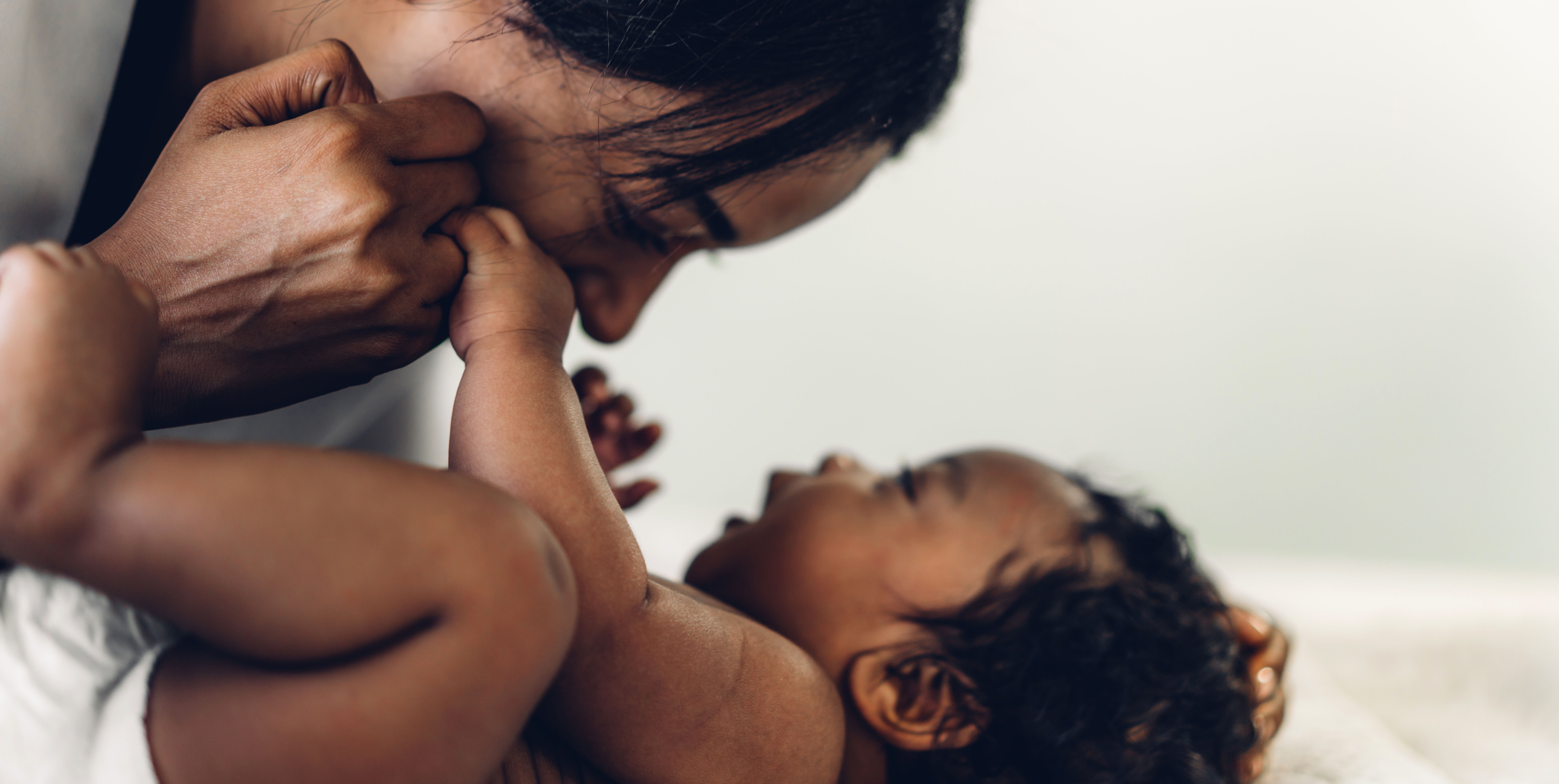 Portrait of enjoy happy love family african american mother playing with adorable little african american baby.Mom touching with cute son moments good time in a white bedroom.Love of black family concept