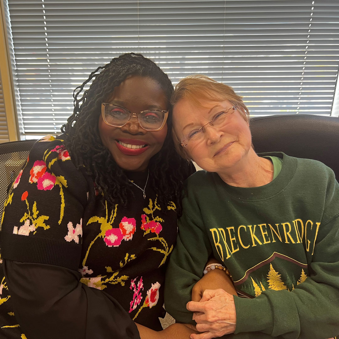 Shemika and Lu sitting together, smiling at the camera