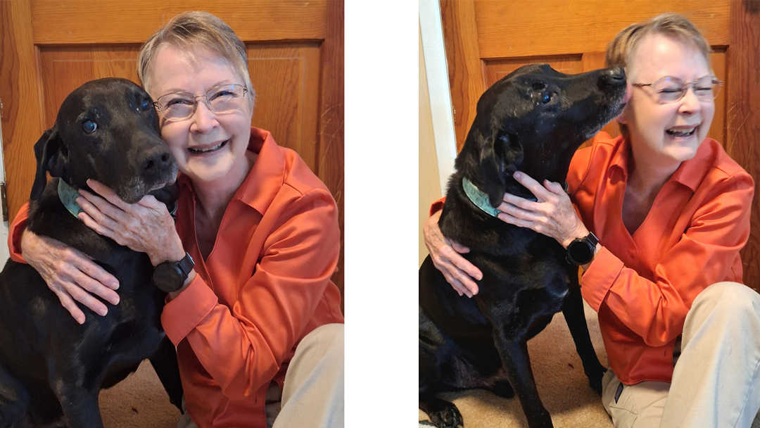 Lu Moseley sitting on the floor with a black lab dog sitting next to her.