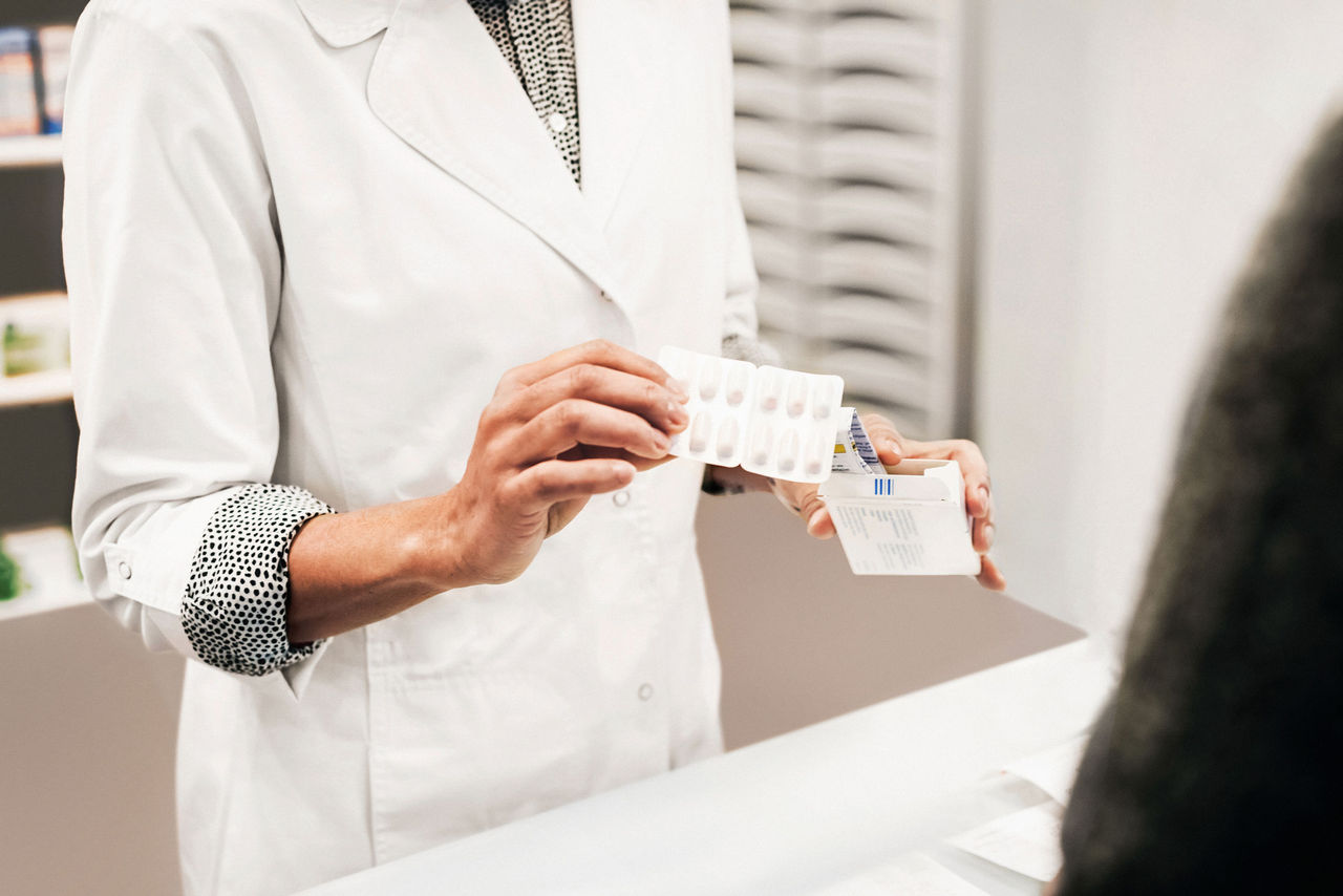person holds a card while looking at a laptop