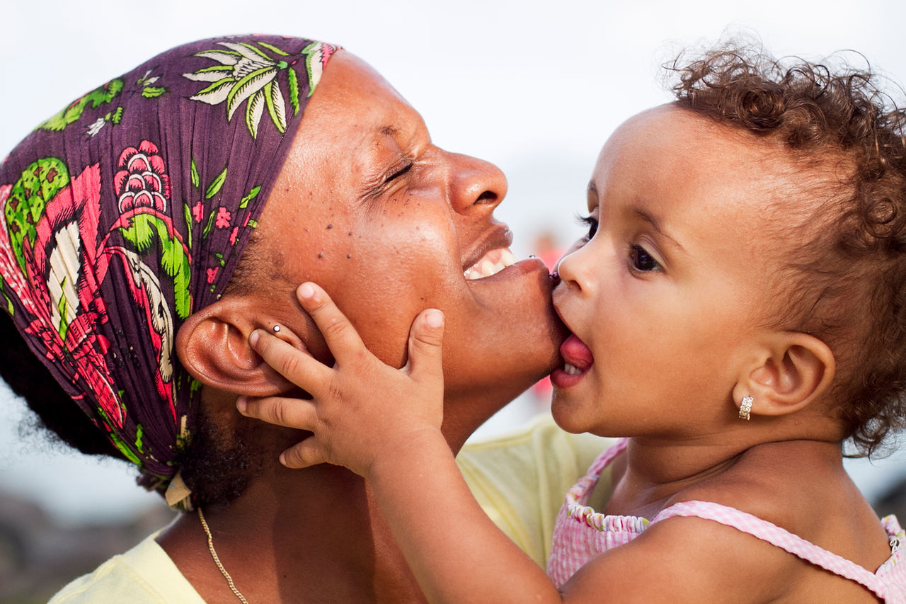 Toddler girl biting and kissing her mother's chin